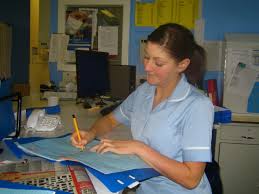 Healthcare worker filling in a form at their desk.