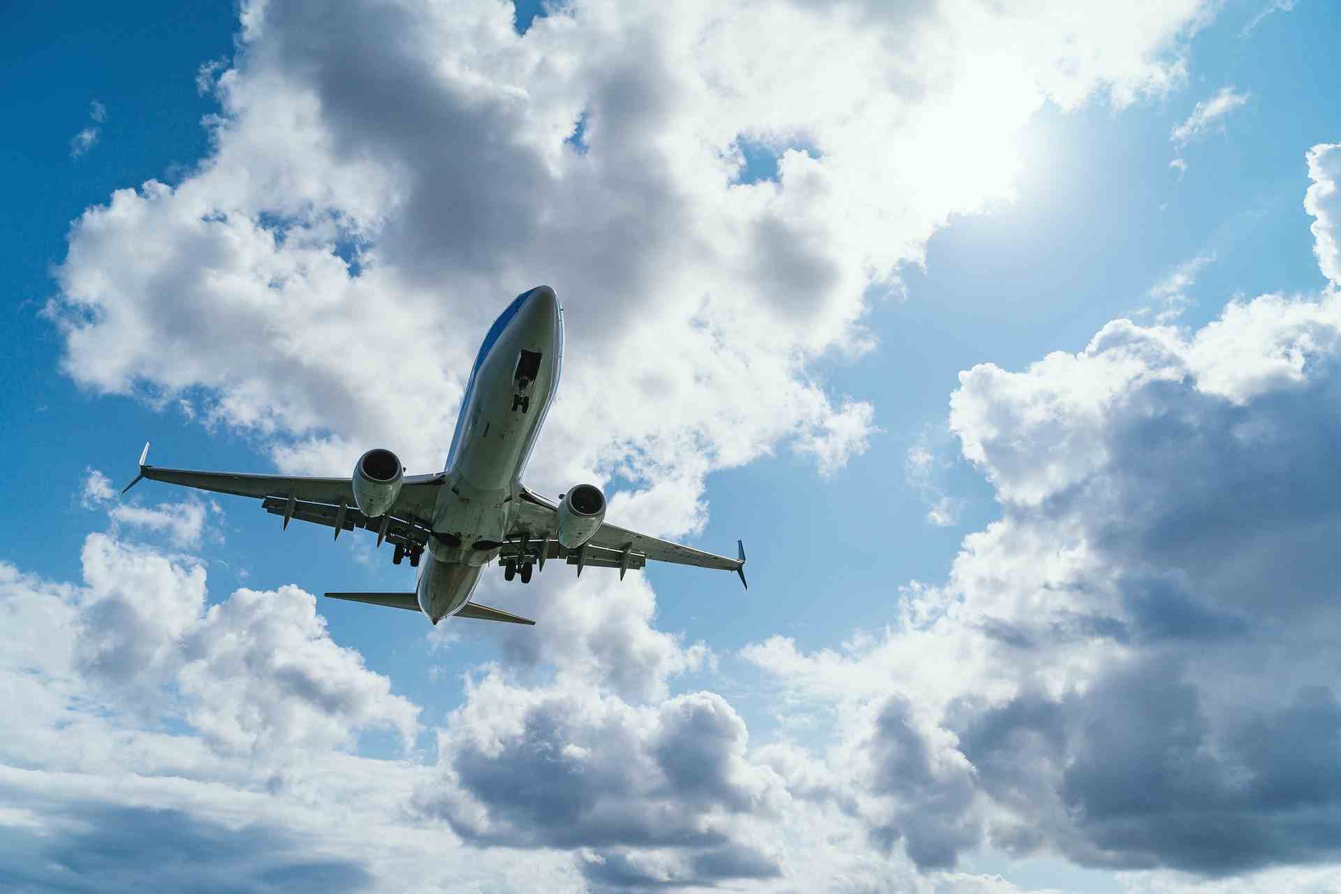 Airplane flying against a blue sky with clouds.