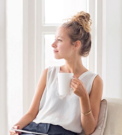 Woman Looking Out of a Window with a Cup of Tea