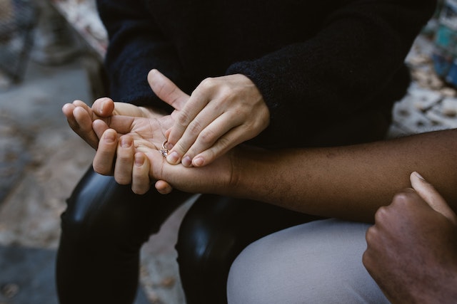 Wife placing wedding band in the hand of husband and returning it to him.