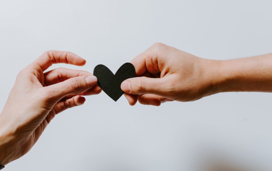 Two hands holding a paper heart.