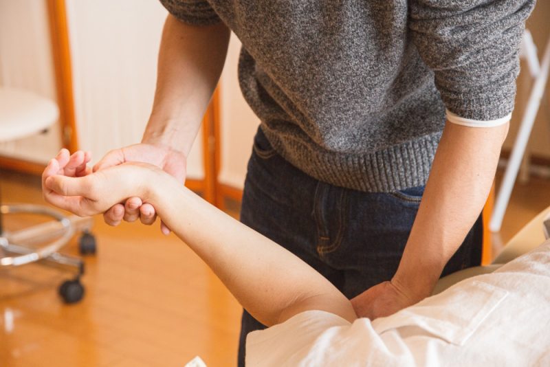 A medical professional assesses a patient's arm.