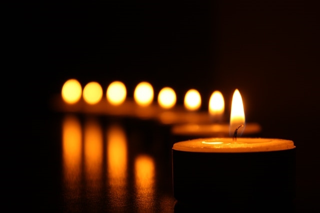 Row of tealight candles glowing in the dark.