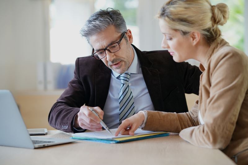 Solicitor in a suit, tie and glasses working with his client.