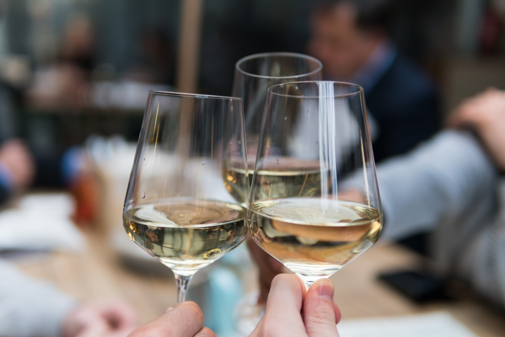 Three glasses of white wine being clinked together.