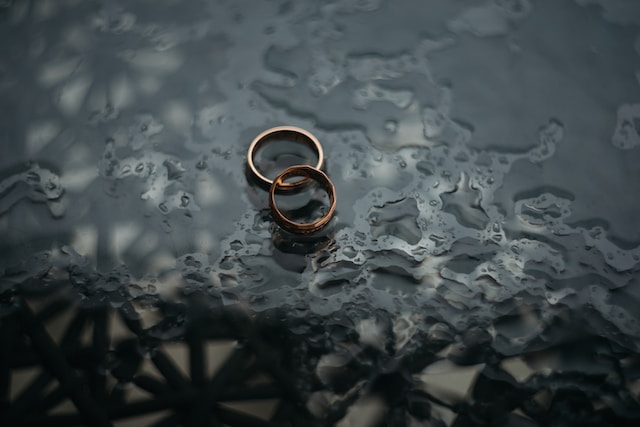 Two wedding bands on a dark table.