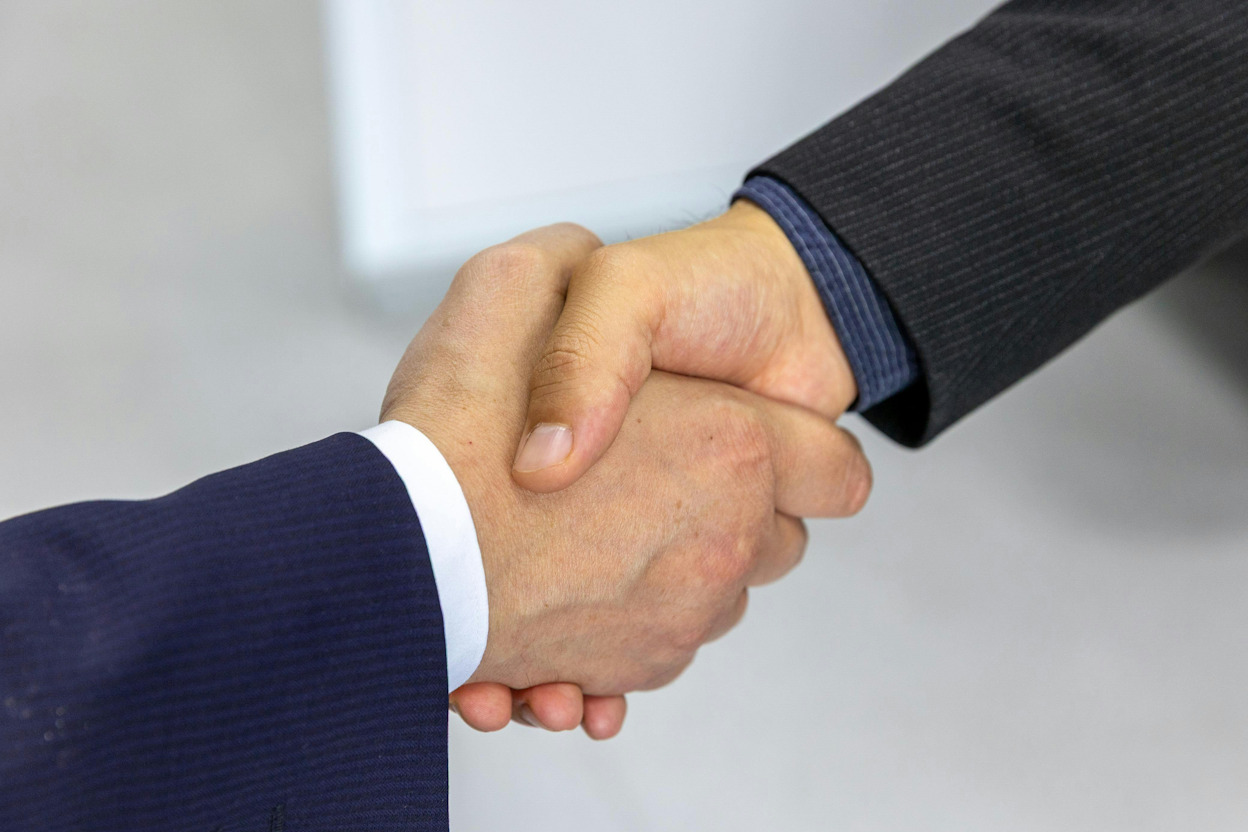 Two hands are clasped in a handshake.
